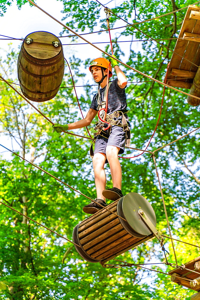 Boy on a floating barrel in the climbing forest and high ropes course, Potsdam Adventure Park, Potsdam, Brandenburg, Germany, Europe