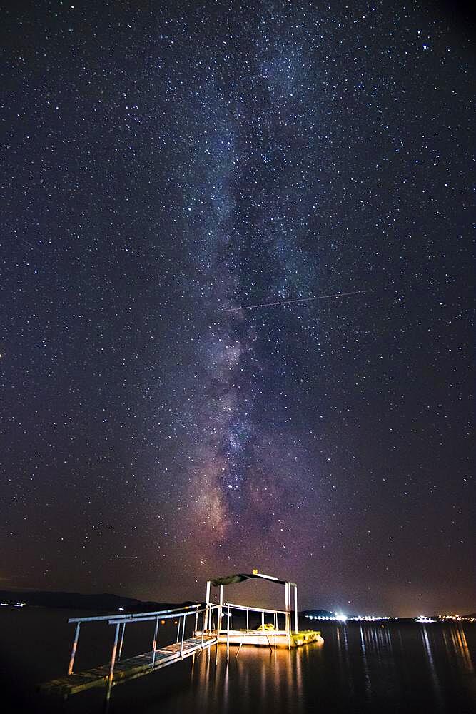 Night view of the Milky Way with illuminated jetty in the foreground, beach, Ouranoupoli, Grichenland, Mediterranean Sea