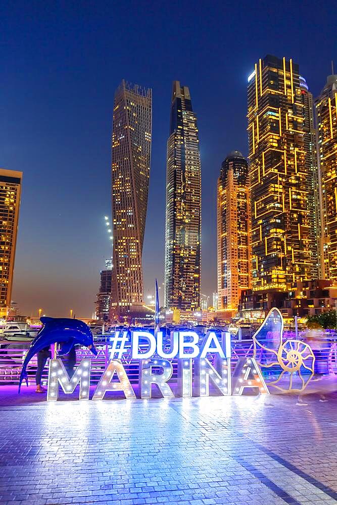 Dubai Marina Logo and Harbour Skyline Architecture Luxury Holiday in Arabia with Boat Yacht by Night in Dubai, United Arab Emirates, Asia