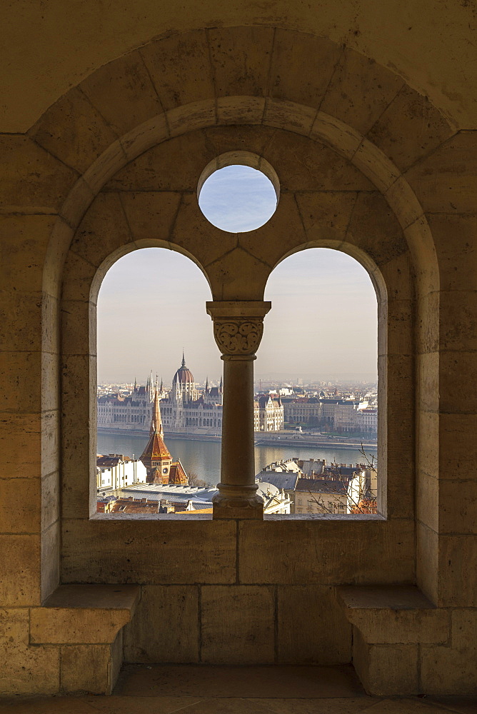 View through an arched window of the Fishermen's Bastion onto the Danube with the Parliament Building, Budapest, Hungary, Europe