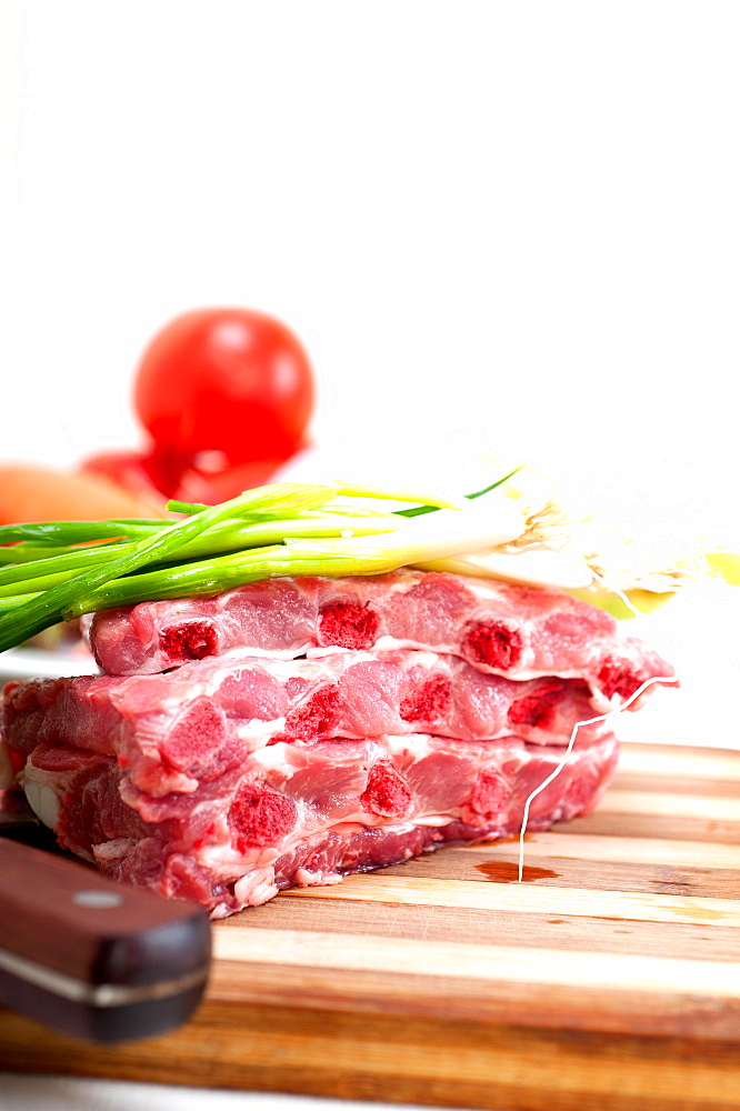 Chopping fresh pork ribs with vegetables and herbs ready to cook