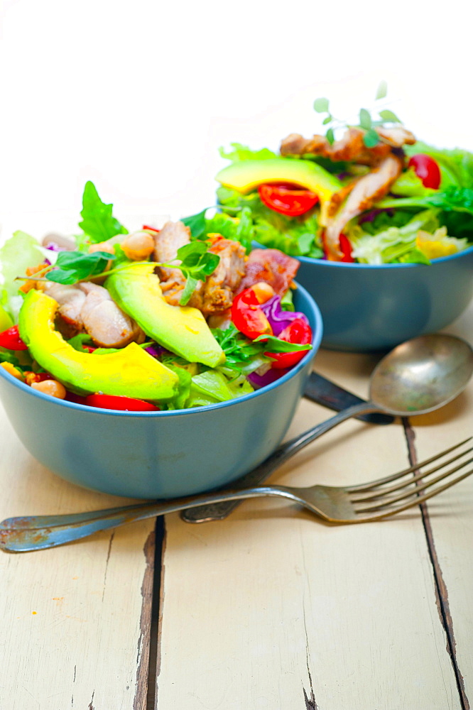 Fresh and healthy Chicken Avocado salad over rustic wood table