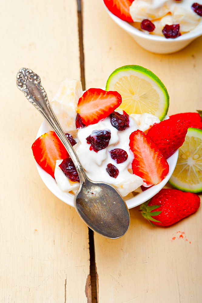 Fruit and yogurt salad healthy breakfast over white wood table