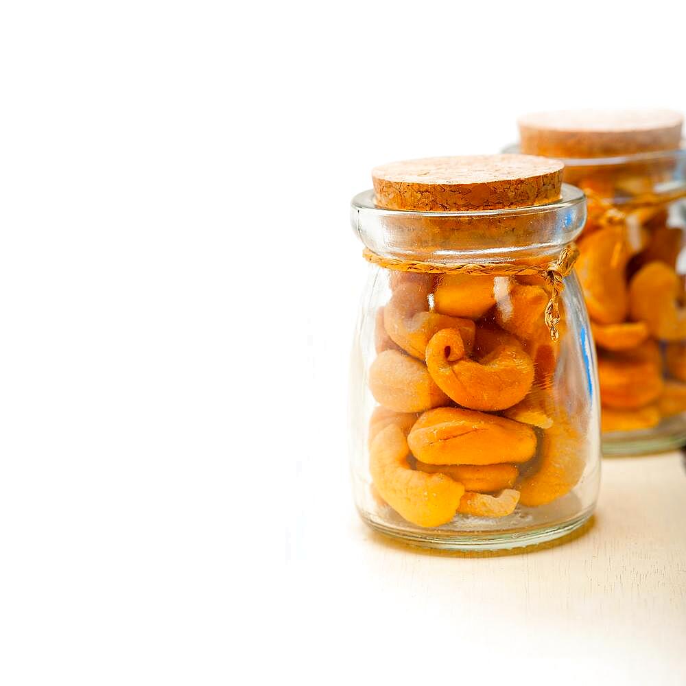 Cashew nuts on a glass jar over white rustic wood table