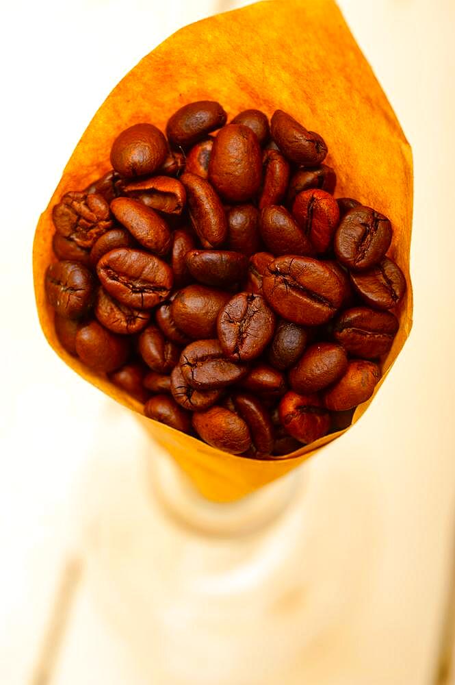 Espresso coffee beans on a paper cone cornucopia over white background