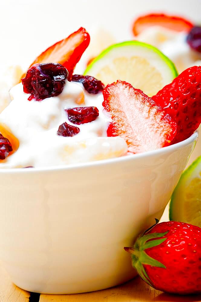 Fruit and yogurt salad healthy breakfast over white wood table