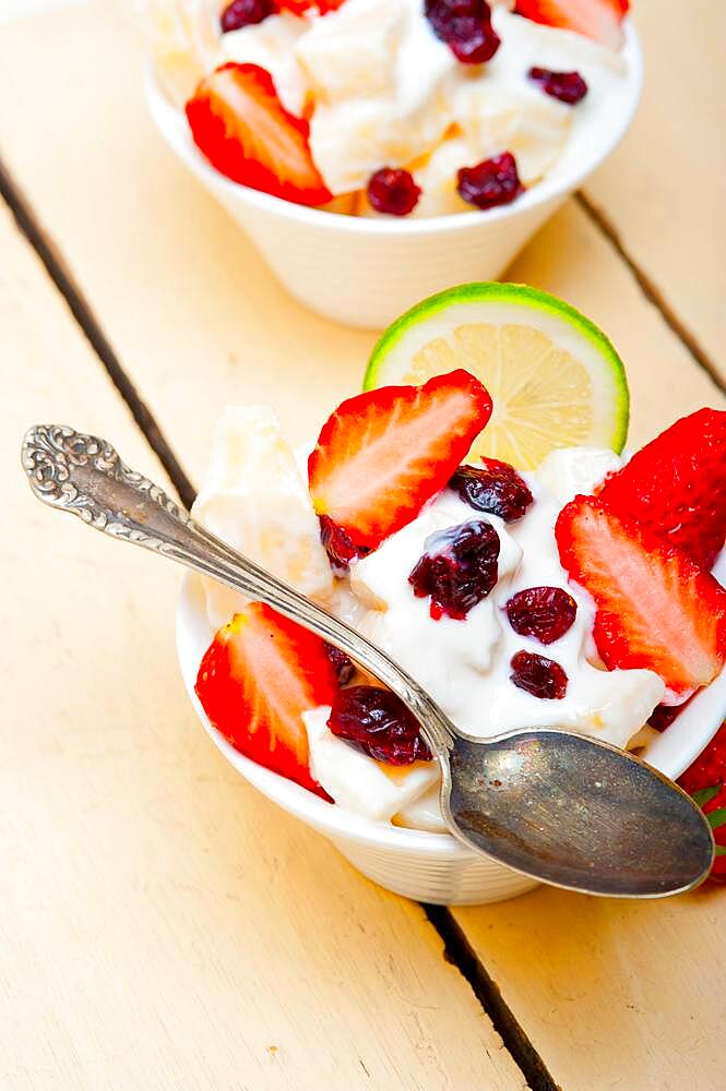 Fruit and yogurt salad healthy breakfast over white wood table