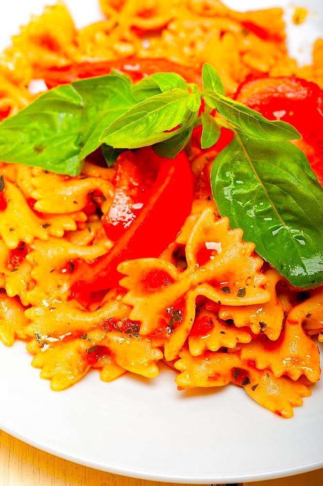 Italian pasta farfalle butterfly bow-tie with tomato basil sauce over white rustic wood table