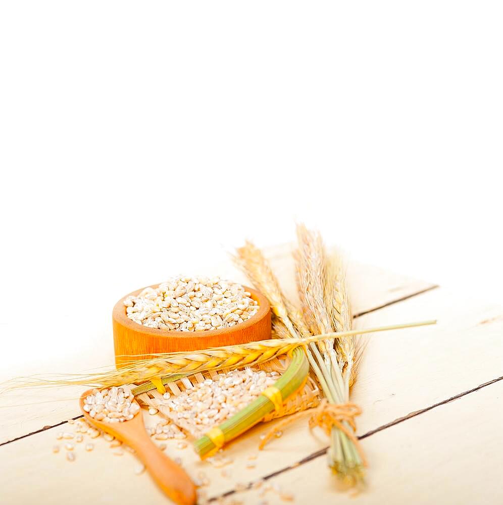 Organic wheat grains over rustic wood table macro closeup