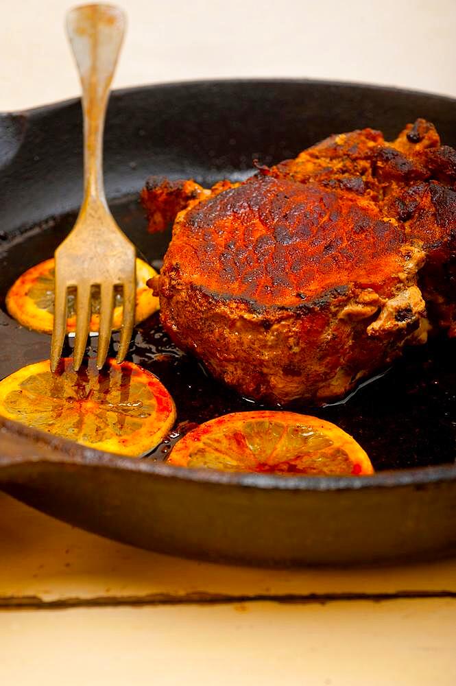 Pork chop seared on iron skillet with lemon and spices seasoning