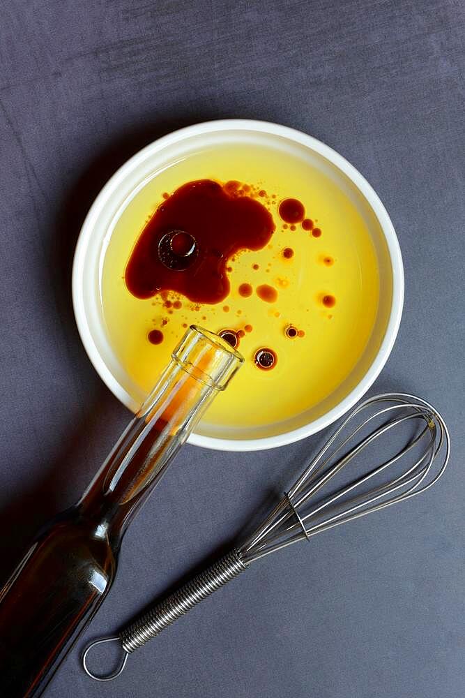 Bowl with cooking oil and aceto balsamico, bottle and whisk