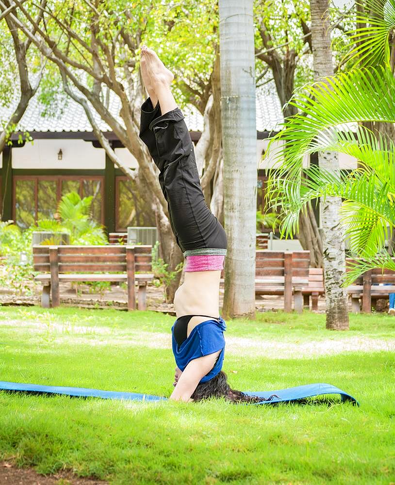 Girl doing headstand yoga, woman doing yoga outdoors lifting feet up, girl doing yoga with both legs up