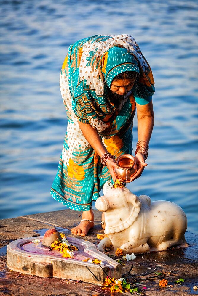 MAHESHWAR, INDIA, APRIL 26: Indian woman performs morning pooja on sacred river Narmada ghats on April 26, 2011 in Maheshwar, Madhya Pradesh, India. To Hindus Narmada is one of 5 holy rivers of India