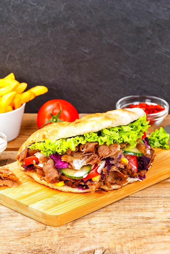 Doener Kebab Doner Kebap fast food meal in pita bread menu with fries on wooden board in Stuttgart, Germany, Europe