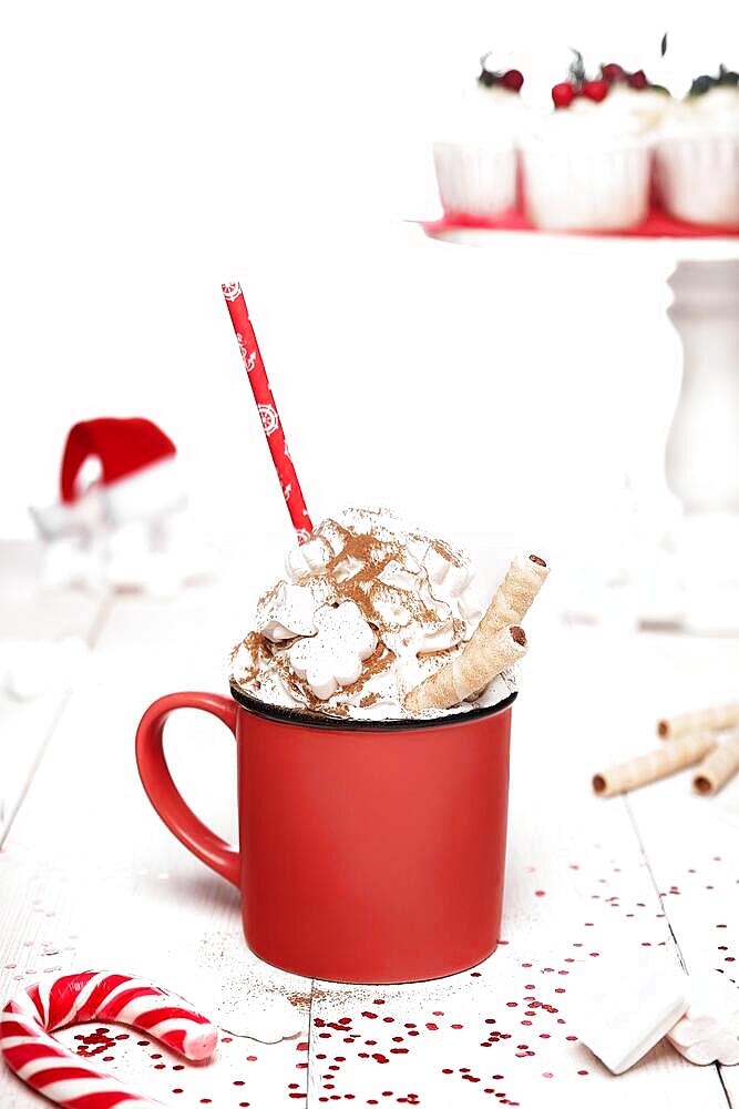 Delicious cocoa with whipped cream, cinnamon and marshmallows on white wooden background with Christmas decor