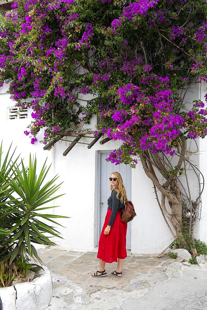 Young woman with red skirt in the alleys of the old town Chora, large purple bougainvillea, Mykonos Town, Mykonos, Cyclades, Greece, Europe