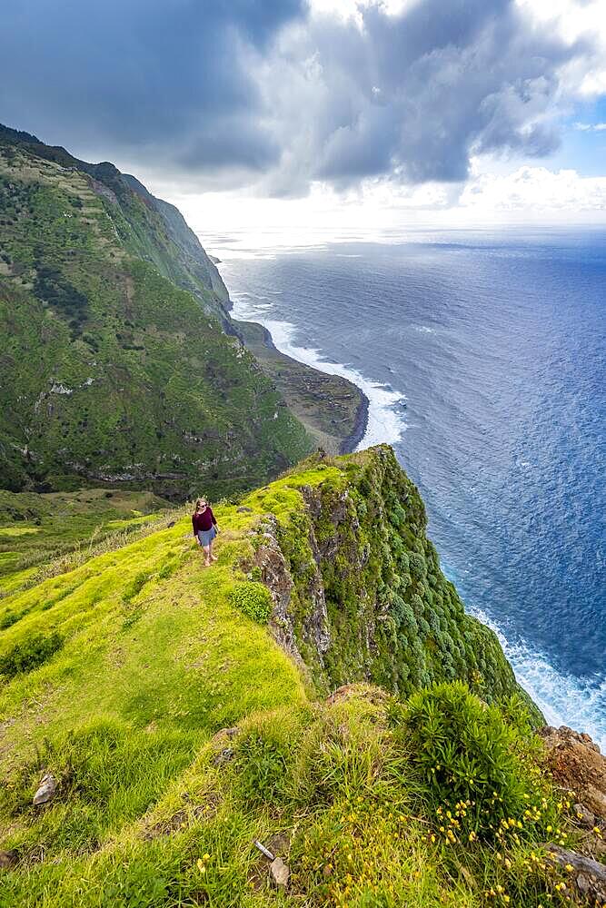 Young woman enjoying view of cliffs and sea, coastal landscape, viewpoint Ponta da Leideira, near Calhau das Achadas, Madeira, Portugal, Europe