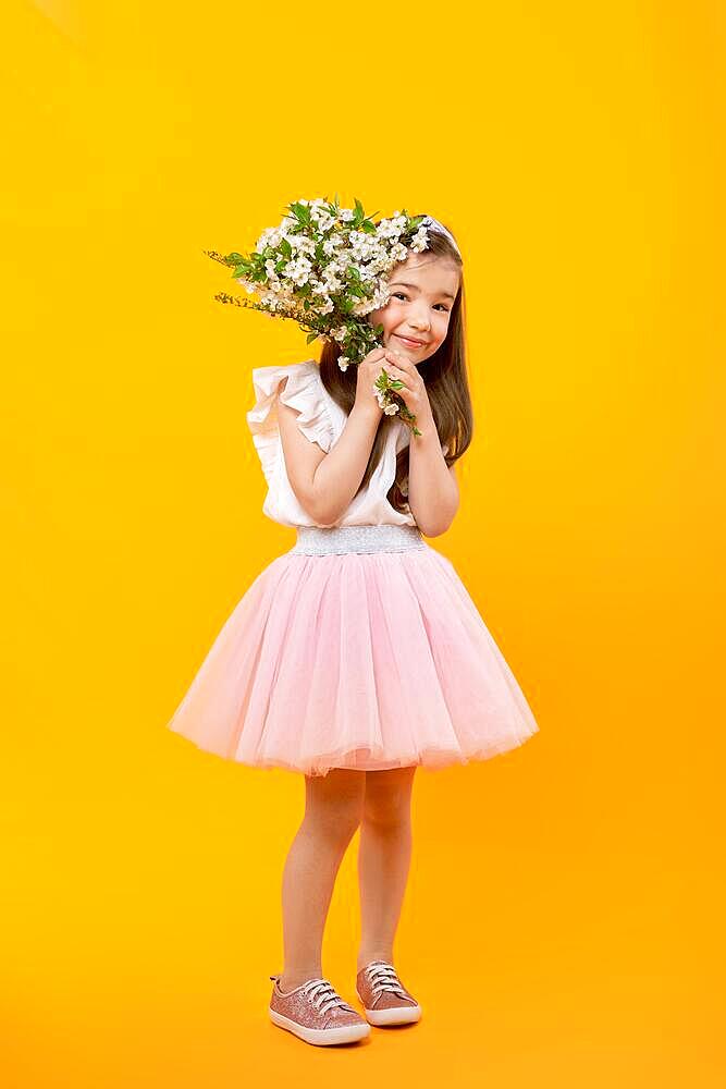 Full body portrait of cute little girl with spring flowers in hands