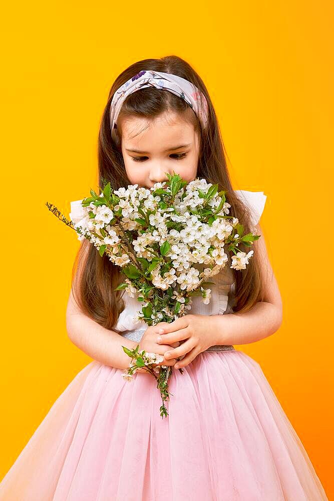 Cute little child sniffing the bouquet of spring flowers