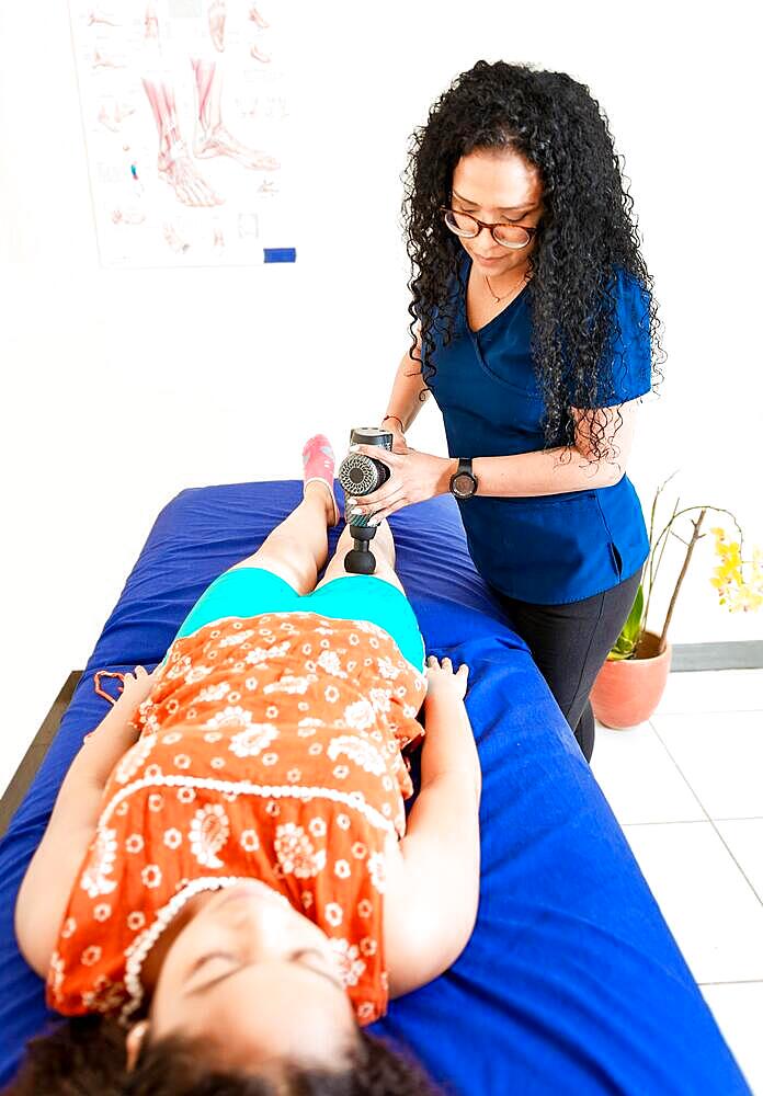 Woman physiotherapist using vibration gun to relieve muscle pain, Physiotherapist using massage gun on female patient. Chiropractor using massage gun on female patient