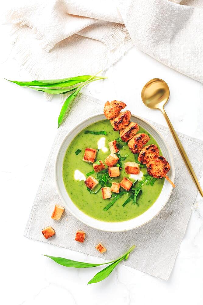 Ramson or bear leek soup with crouton, sour cream and turkey skewer on white background