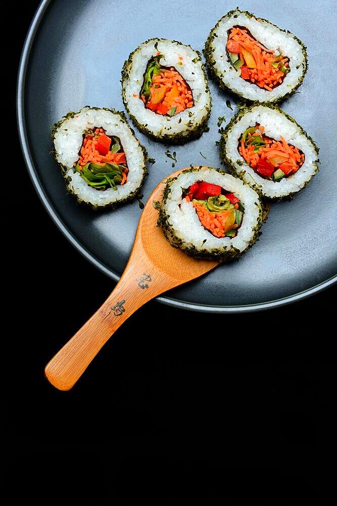 Vegetarian sushi, sushi filled with vegetables on plate with wooden ladle