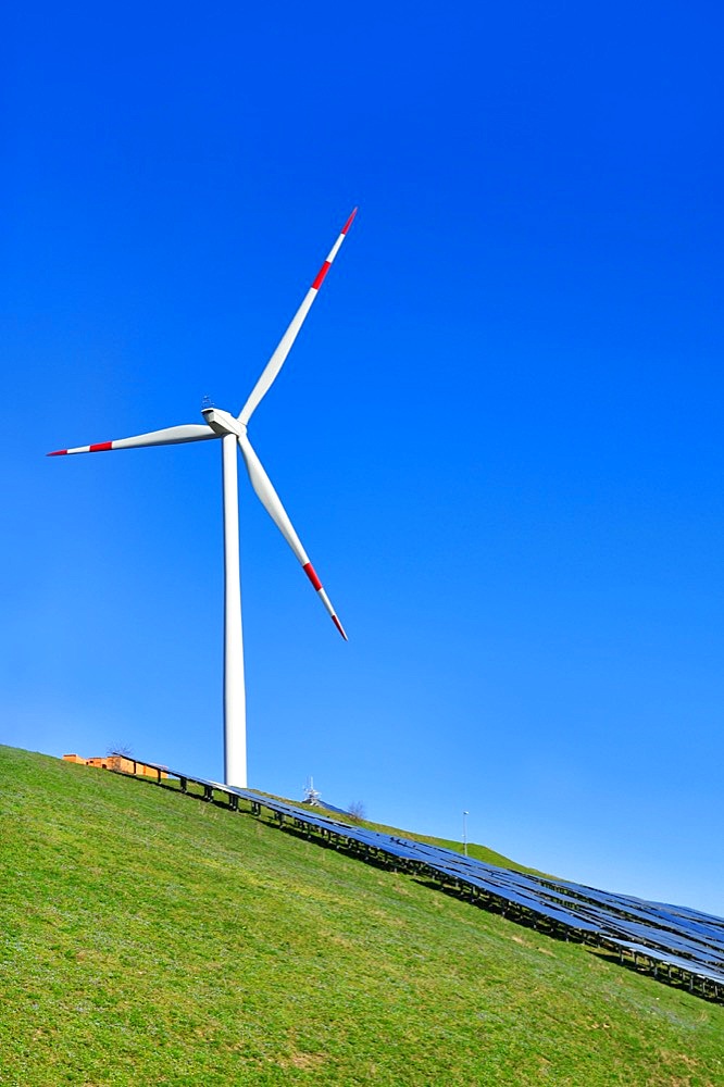 Renewable wind and solar energy. Wind turbine next to photovoltaic system on hill