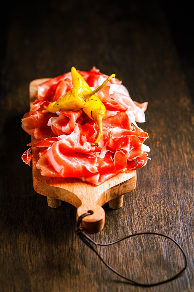 Prosciutto with grilled peppers - Italian dry ham with grilled green peppers on wooden table