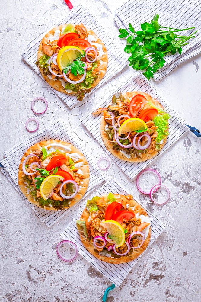 Greek gyros meat with pita flat bread, vegetables and onions and Tzatziki dip on white background