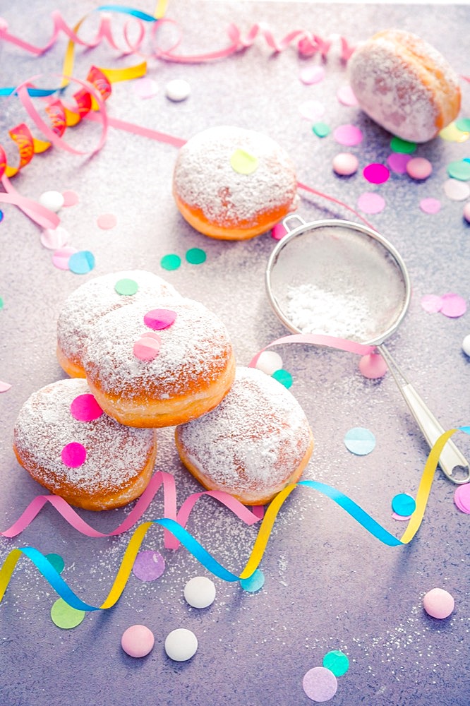 Traditional Berliner for carnival and party. German Krapfen or donuts with streamers and confetti. Colorful carnival or birthday image