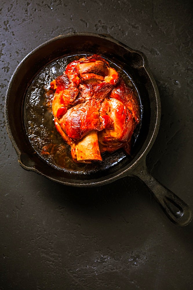 Traditional German cuisine - Roasted pork knuckle eisbein (Schweinshaxe) in iron pan on black background