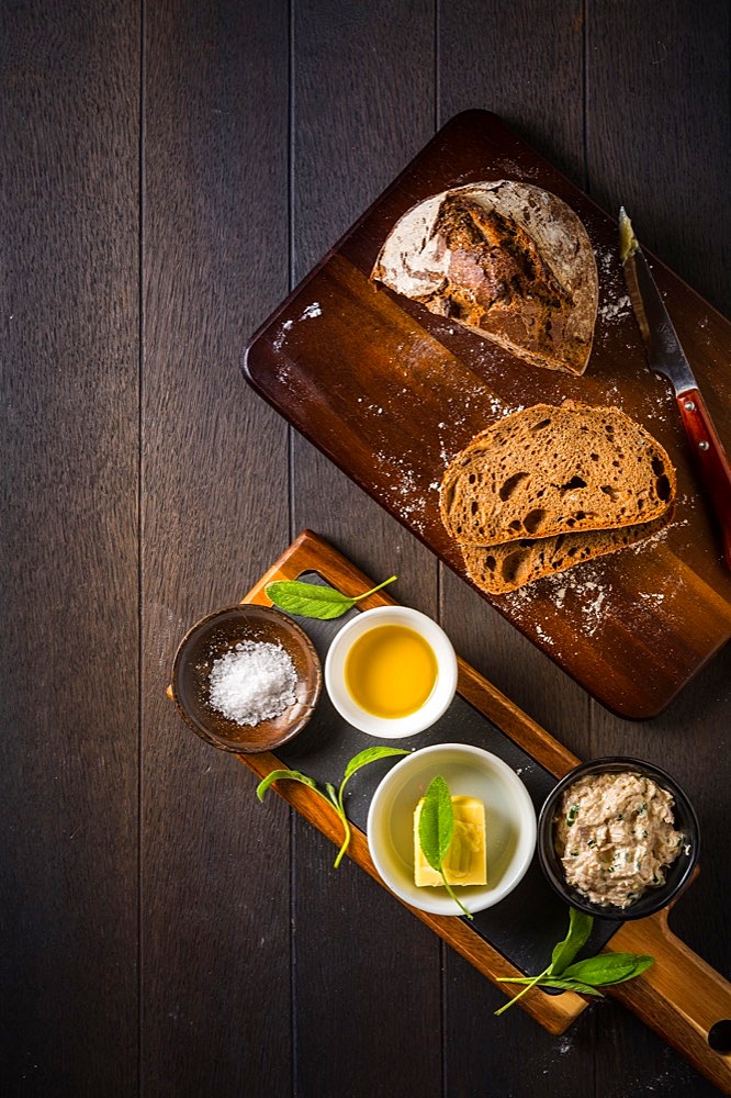 Spelt bread with homemade tuna spread, olive oil and salt on wooden background