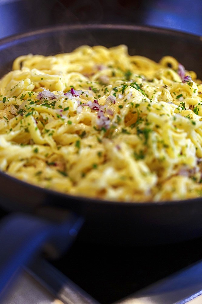 Swabian Kaesspaetzle with onions and herbs stew in a pan