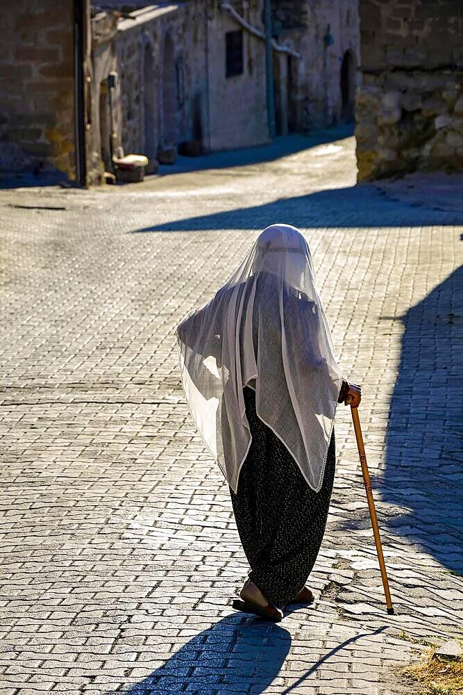 Old lady wearing the clothes and Islam veil walking the streets of Goreme in Cappadocia, Turkey, Capadocia, Goreme, Brasil, Asia