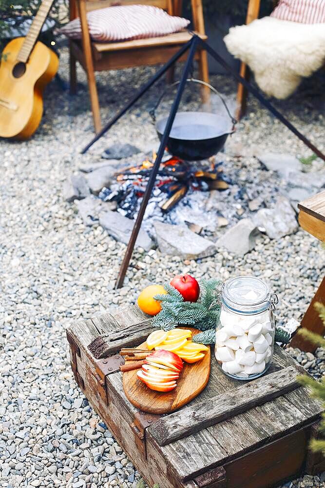 From above traditional mulled wine with slices of orange preparing in pot over burning logs in winter in countryside