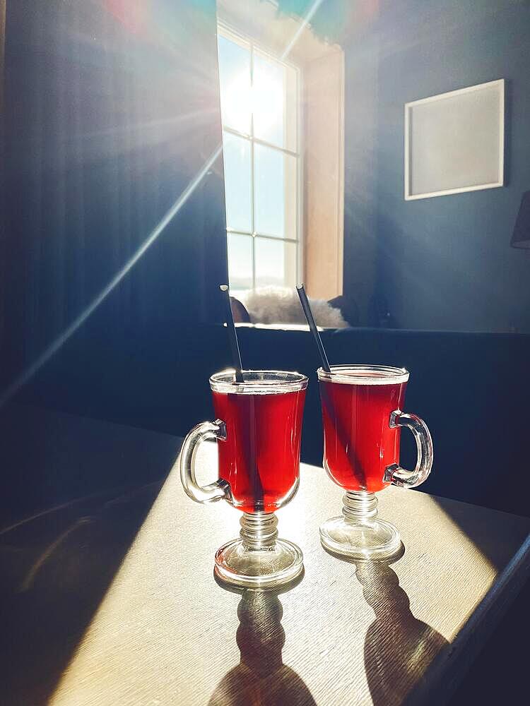 Two glasses of mulled wine on the windowsill overlooking the winter mountains. Winter hot drink