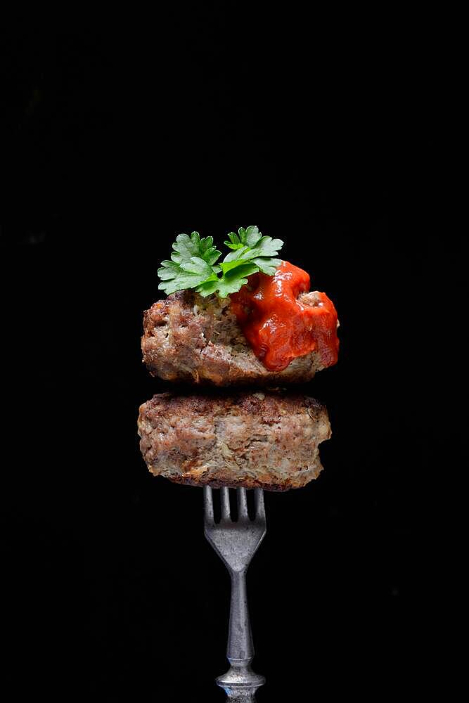 Two homemade meatballs on fork, minced meat