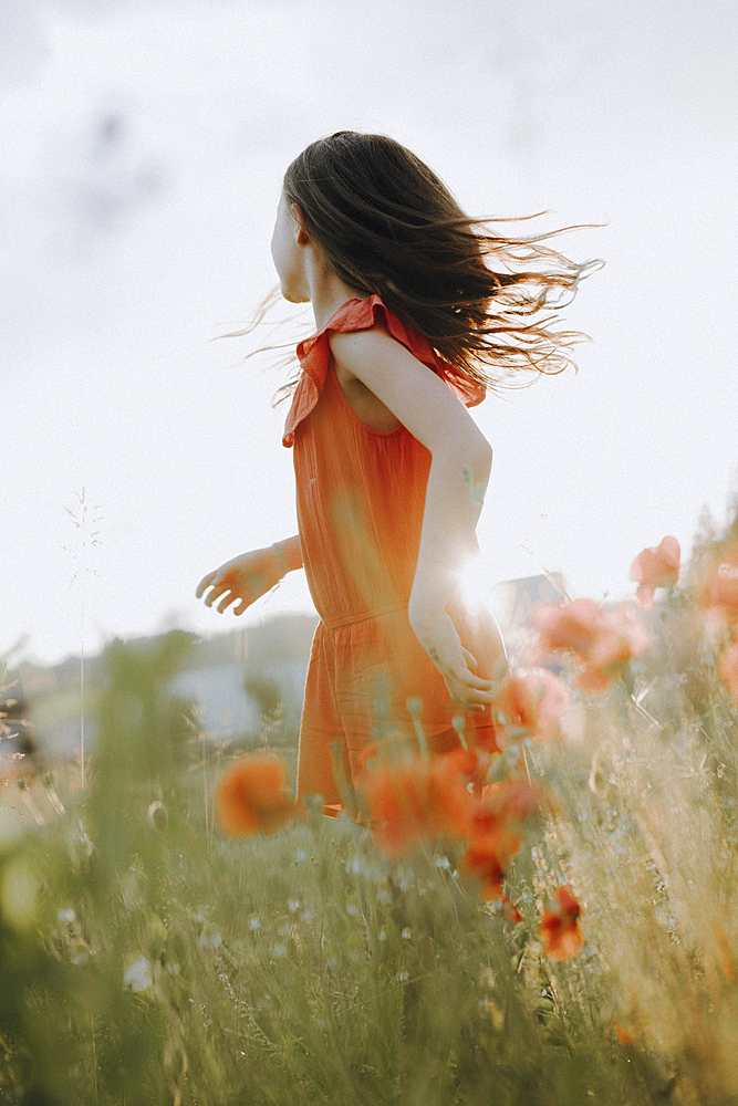 Girl in a red dress in a poppy meadow