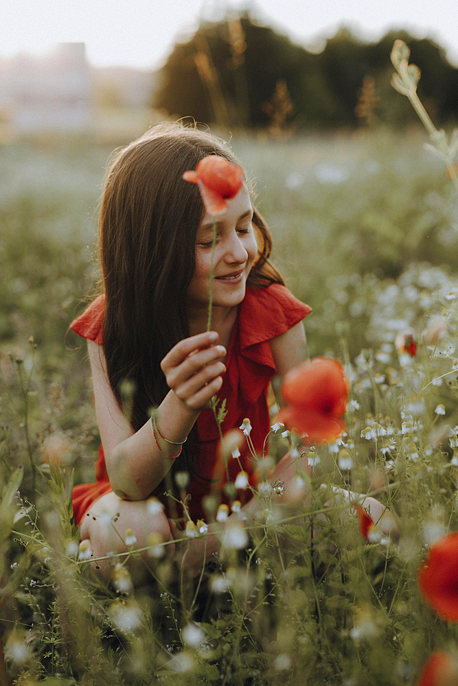 Girl in a red dress in a poppy meadow