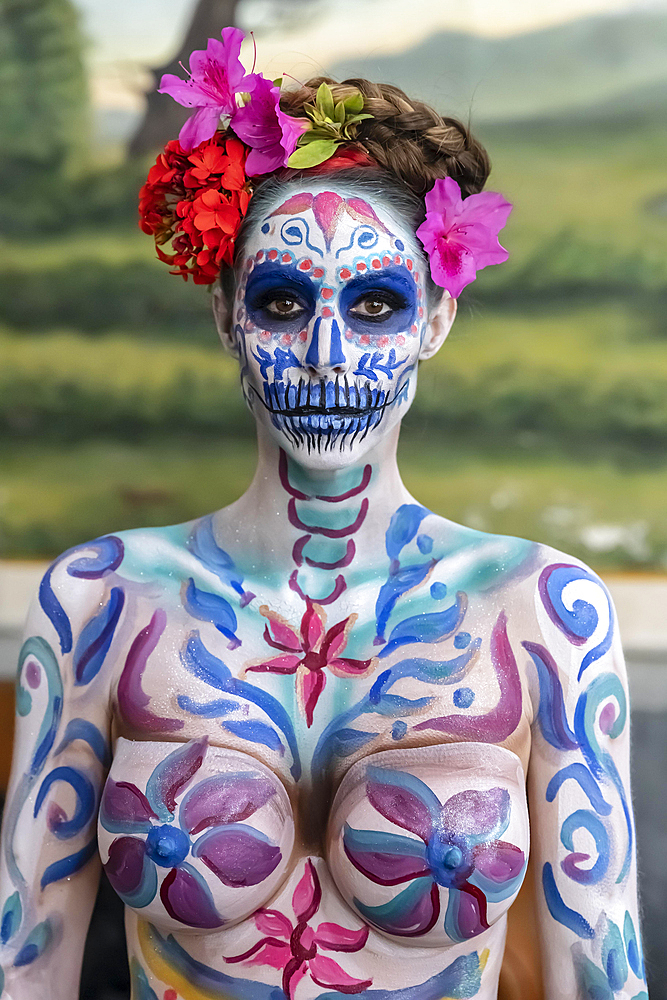 A gorgeous Hispanic Brunette model poses with traditional skull sugar makeup paint for a Mexican festival