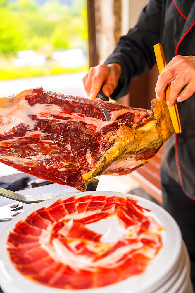 Detail of a man cutting Iberian ham at a wedding. Service of a person cutting a piece of ham. Chef or cutter with a knife cutting slices. traditional food of spain