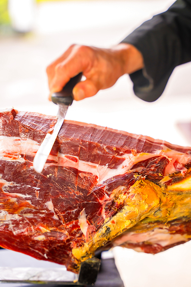 Detail of a man cutting Iberian ham at a wedding or event. Service of a person cutting a piece of ham. Cook or cutter with a knife. traditional food of spain