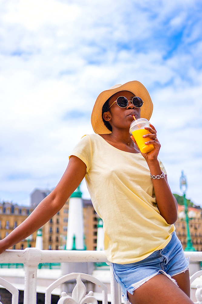 Portrait of black ethnic woman having an orange juice enjoying the summer