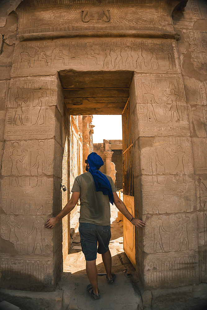 Portrait of a young man with a blue turban at the entrance to the Edfu Temple near the city of Aswan. Egypt, west bank of the nile in the city of Edfu, Greco-Roman construction, dedicated to Horus