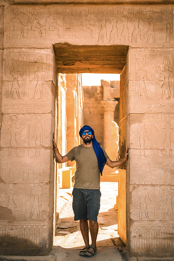 Portrait of a young man with a blue turban at the entrance to the Edfu Temple near the city of Aswan. Egypt, west bank of the nile in the city of Edfu, Greco-Roman construction, dedicated to Horus