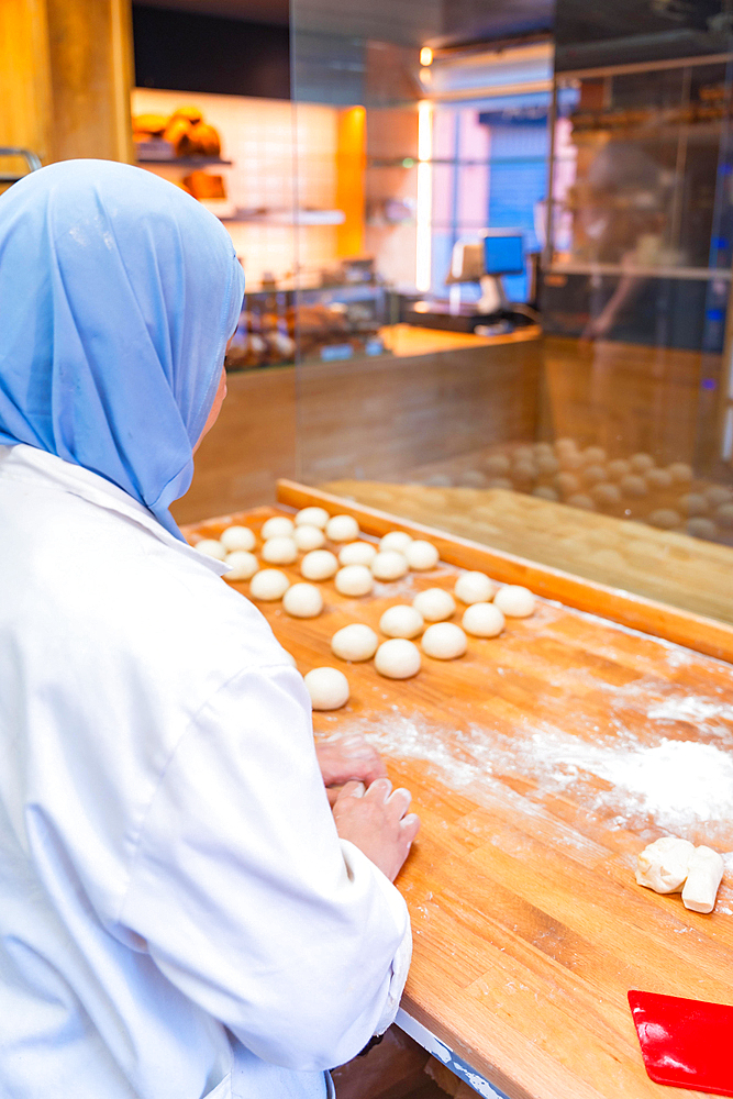 Arab woman baker in the bakery workshop workshop of artisan bakery preparing the bread dough