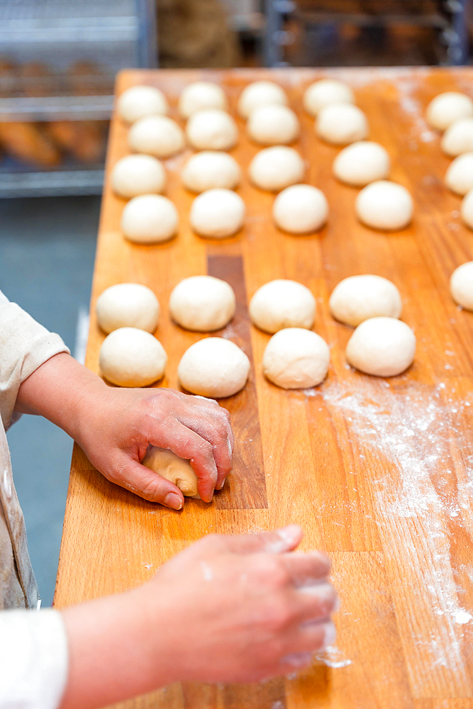 Hands of female baker in the bakery workshop of artisan bakery preparing the bread dough