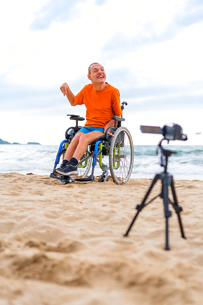 Portrait of a disabled person in a wheelchair recording a video by the beach