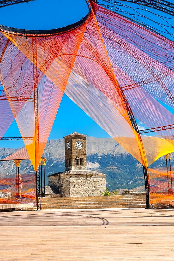 Colored arch in the Ottoman Castle Fortress of Gjirokaster or Gjirokastra and in the background the church with the clock tower. Albania, Kulla e Sahatit