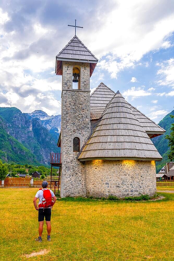 A tourist at the Catholic Church in the valley of Theth national park, Albania. albanian alps